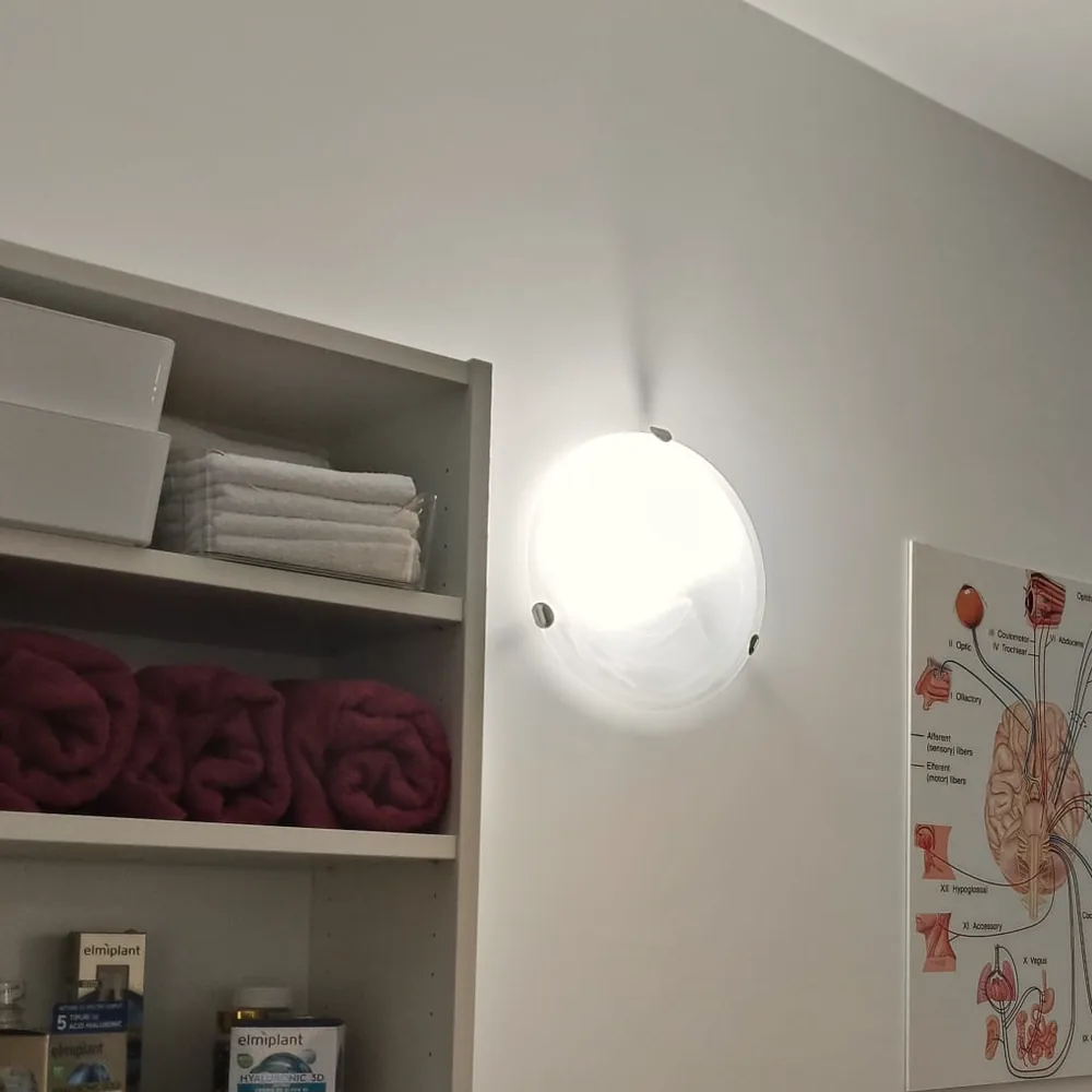 Raftul cu prosoape carmin și albe, sub lampa de perete.
