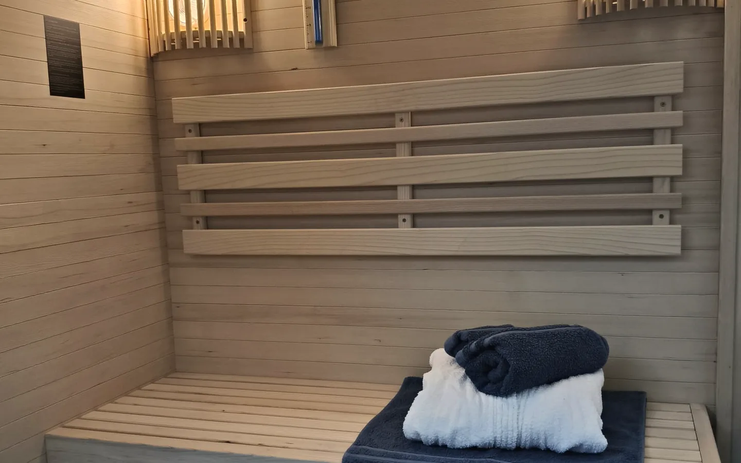 Sauna finlandeză, cu bancă de lemn și prosoape.